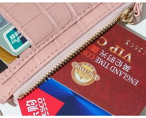 Detail of pink crocodile leather card holder featuring gold zipper and multiple slots