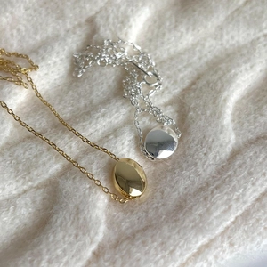 Detailed shot of gold and silver bean pendants on elegant white knit fabric