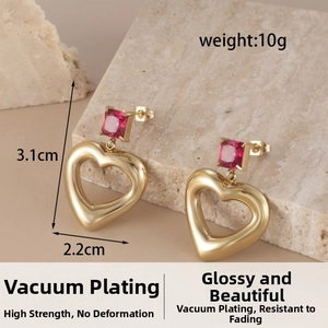 Detail view of heart earrings with red gemstones, size 3.1cm by 2.2cm in gold finish