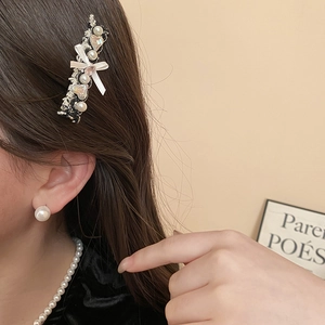 Detail of elegant bow hair clip with pearls and matching earrings worn by a model
