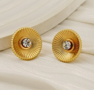 Macro detail of gold-finish radial textured earrings with a central zircon inlay