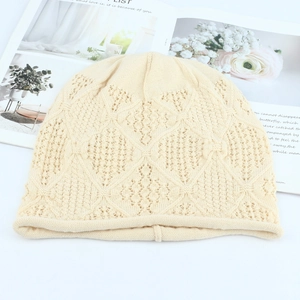 Detail view of cream hollow knit hat with diamond pattern and rolled edge design