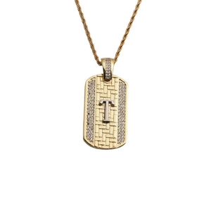 Détail du pendentif doré avec lettre T, zircons sertis et chaîne de style corde