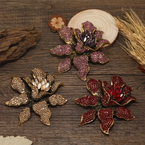 Detailed view of three vintage rhinestone flower brooches in purple, gold, and red tones