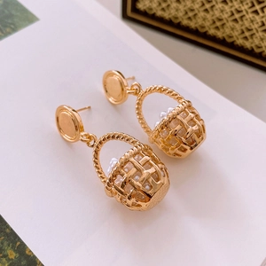 Detail view of gold woven basket earrings with elegant pearls on a white background