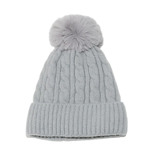 Détails de la maille torsadée et du pompon en fausse fourrure sur bonnet gris