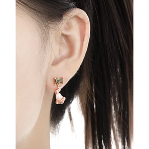 Irregular rose gold drop earring with green zircon and white pearl on a model