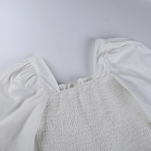 Detalle de escote cuadrado con pecho fruncido y mangas abullonadas en una blusa blanca