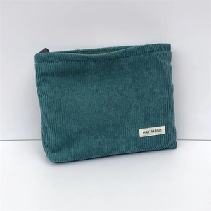 Detail of dark green corduroy makeup bag featuring a zipper and May Rabbit fabric label