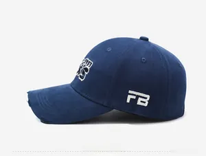 Detail of navy blue baseball cap featuring vintage distressed brim and side embroidery