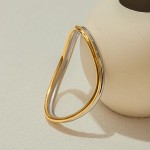 Dettaglio di bracciale rigido a onda in acciaio inossidabile con finitura bicolore oro e argento