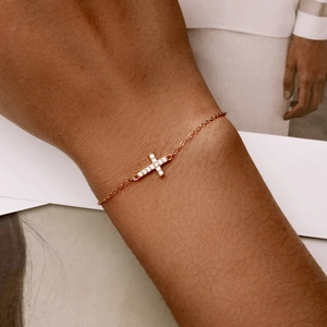 Detailed view of rose gold cross bracelet with clear pavé stones on model wrist