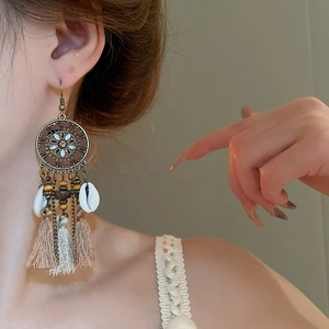 Close-up of bohemian tassel earrings with turquoise beads and shell detail on a model