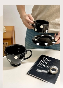 Détail d'un ensemble de tasses en céramique noire à pois blancs avec anse ronde