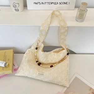 Close-up of cream textured floral bag with a decorative multi-color beaded shoulder strap