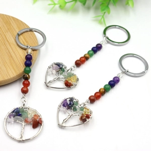 Three colorful crystal tree of life keychains with gemstone chips and chakra beads on wood