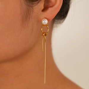 Detail view of gold tassel earrings with pearls on a model for a stylish modern look