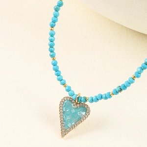 Macro detail of turquoise beaded necklace featuring a crystal-encrusted heart pendant