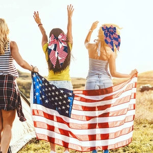 Outdoor shot showing two women wearing American flag bow hair clips in a festive setting