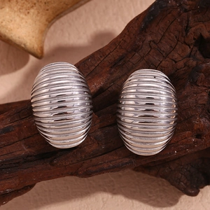 Macro view of silver oval stud earrings with horizontal striped texture on wood