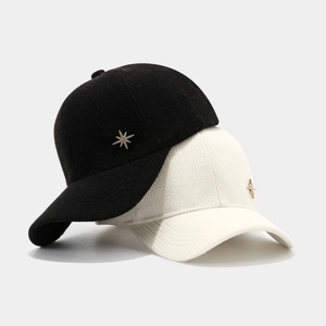 Black and beige knit baseball caps with gold star emblems on light grey background