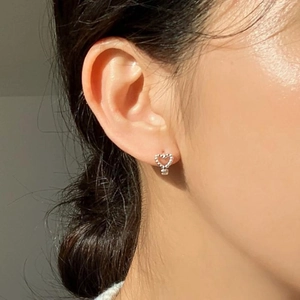 Detail of silver heart stud earring with beaded texture worn by model for style