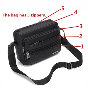 Detail view of black crossbody bag featuring five functional zippered compartments and metal tag