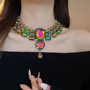 Macro detail of chunky statement necklace featuring iridescent rhinestones on a gold base