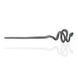 Macro detail of black snake hair pin featuring green gemstone eyes and scales