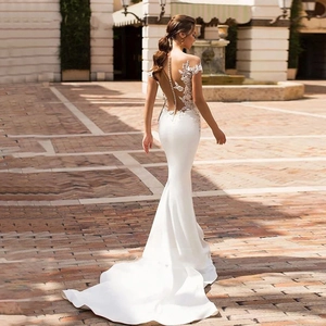 Elegant white mermaid bridal gown with lace appliques and long train seen from the back