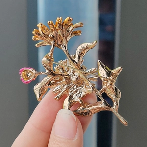 Detail of golden floral brooch back showing secure pin structure and pink enamel accents