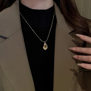 Detail of vintage gold oval necklace with faux tiger eye stone worn by a model