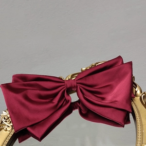 Detail of red satin bow hair clip on a gold embossed mirror with elegant glossy texture