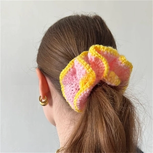 Detailed view of handmade pink knit scrunchie with yellow trim on a ponytail hair