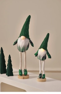Close-up of green knitted Christmas gnomes with warm LED lights and plush textures