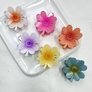 Top view of six colorful gradient flower hair claws on a white square plate for styling