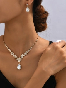 Detailed view of teardrop necklace and earrings set with sparkling crystals on a model
