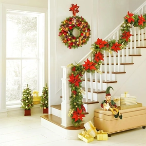 Christmas wreath and garland with red poinsettia and warm LED lights on stairs