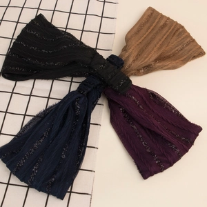 Close-up of four elastic ribbed headbands in black, brown, navy, and purple with metallic finish