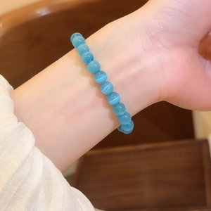 Vista macro detallada de una pulsera de cuentas de piedra de ojo de gato azul en muñeca