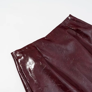 Dettaglio della trama in pelle verniciata rosso vino e vita della gonna