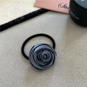 Detailed shot of blue-grey velvet rose elastic hair tie on a grey textured surface