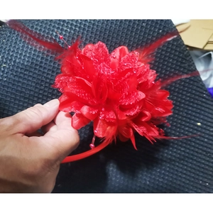 Detail of red flower headpiece with mesh netting and elegant feathers for parties