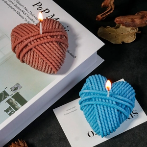 Creatieve hartvormige gebreide wolbal geurkaarsen in blauw en roze op een boek