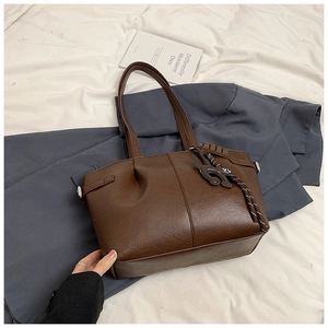 Detailed view of dark brown pleated tote bag with faux leather texture and charm