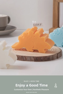 Detail of orange stegosaurus scented candle on wood slice base with decorative tag