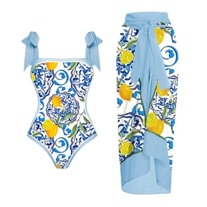 Lemon print one-piece swimsuit and blue ceramic pattern sarong set on white background