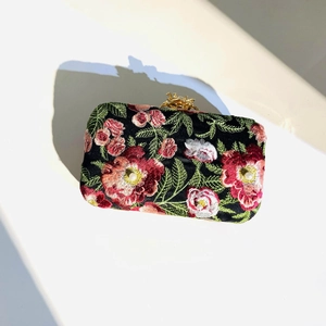 Detailed embroidery with red and pink flowers and tiny pearls on a black clutch bag
