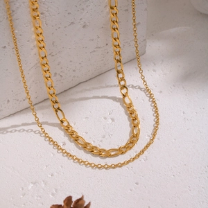 Double layered gold stainless steel Figaro chain necklace on textured white stone