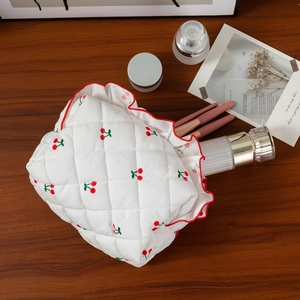Détail de la trousse de maquillage matelassée cerise montrant l'intérieur avec produits de soin